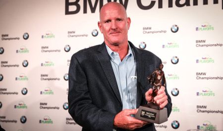 Joe LaCava in a black coat and white shirt holding a trophy.